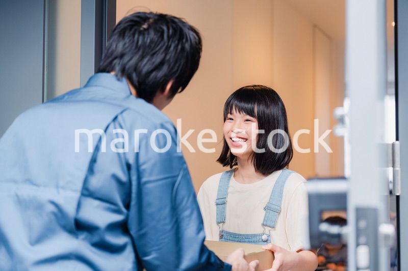 家で宅配便を受け取る小学生の女の子