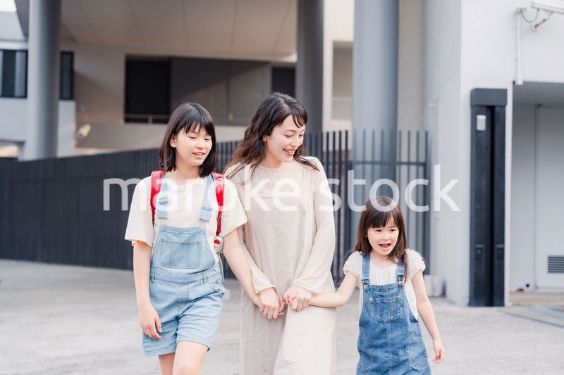 お母さんと手を繋いで学校に行く2人の女の子