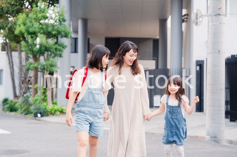 お母さんと手を繋いで学校に行く2人の女の子