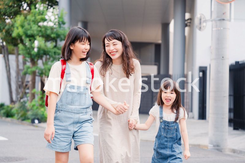 お母さんと手を繋いで学校に行く2人の女の子