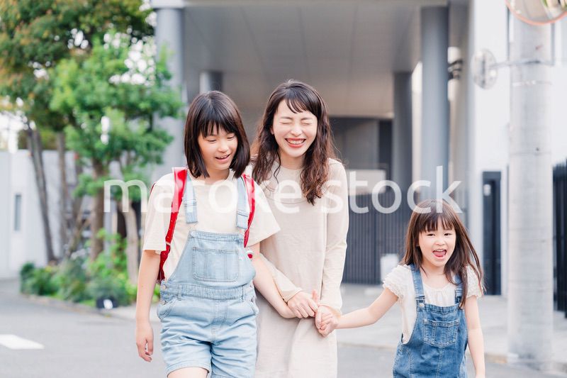 お母さんと手を繋いで学校に行く2人の女の子