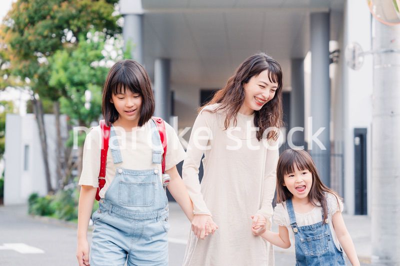 お母さんと手を繋いで学校に行く2人の女の子