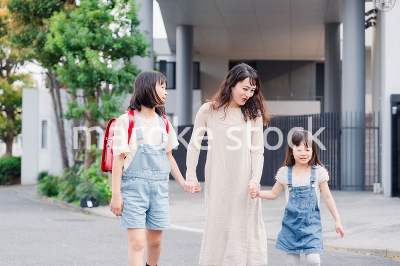 お母さんと手を繋いで学校に行く2人の女の子