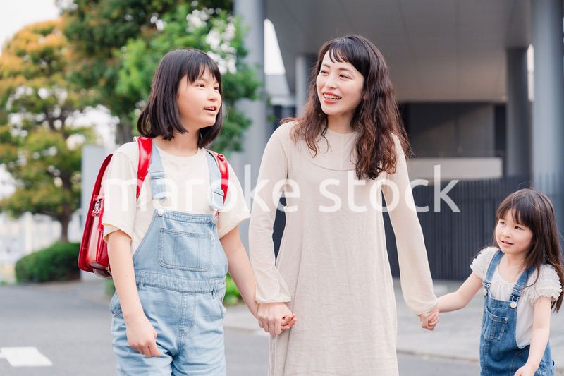 お母さんと手を繋いで学校に行く2人の女の子