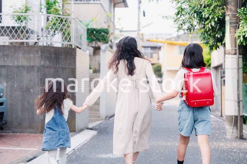 お母さんと手を繋いで学校に行く2人の女の子