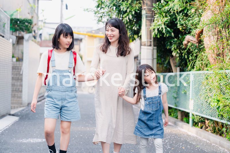 お母さんと手を繋いで学校に行く2人の女の子