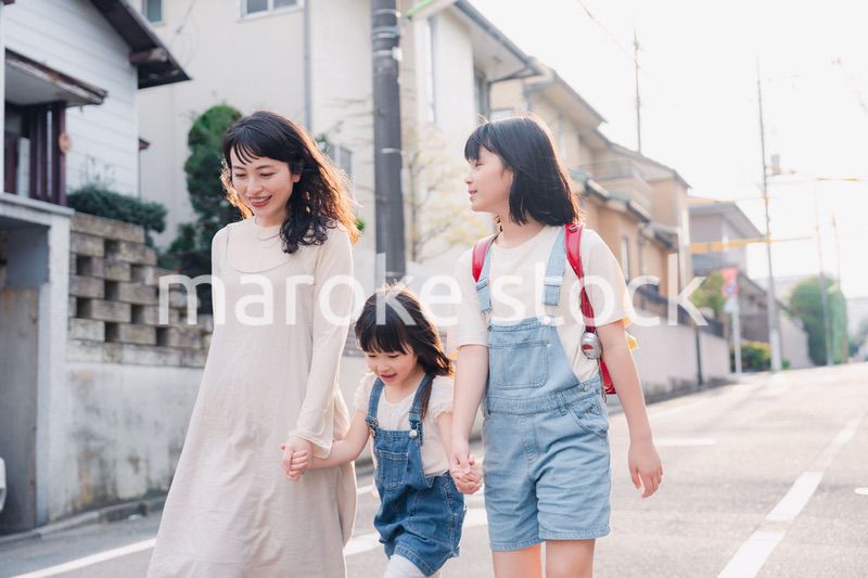 お母さんと手を繋いで学校に行く2人の女の子