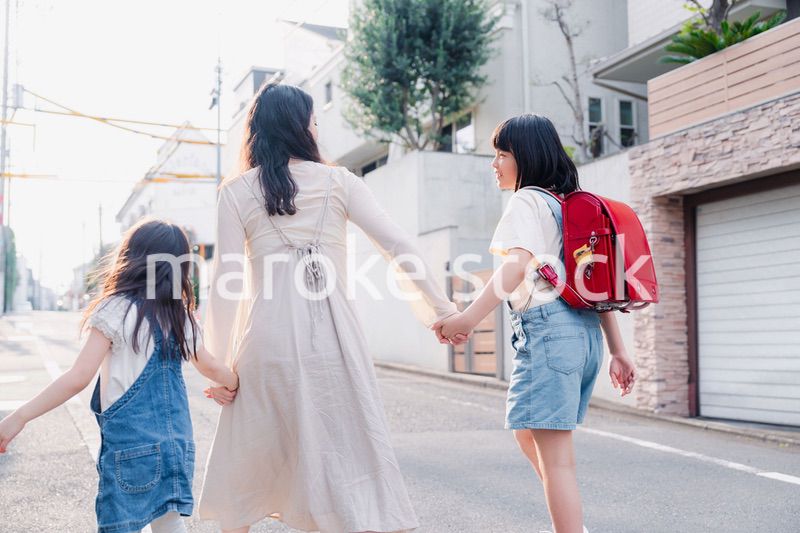 お母さんと手を繋いで学校に行く2人の女の子