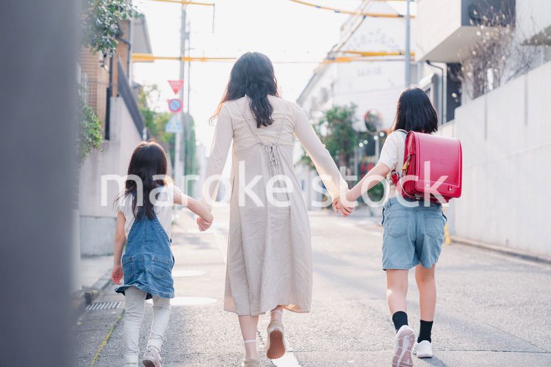 お母さんと手を繋いで学校に行く2人の女の子