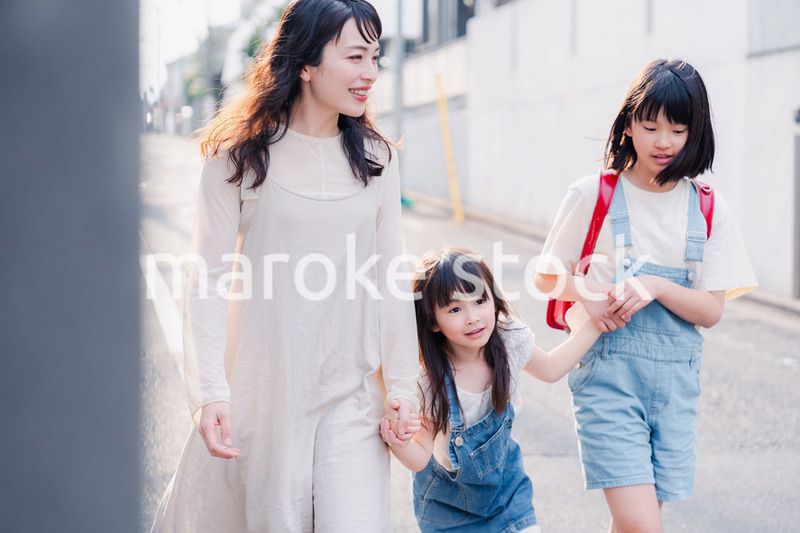 お母さんと手を繋いで学校に行く2人の女の子