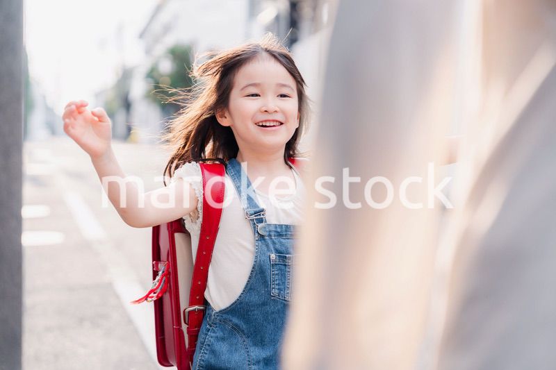 ランドセルを背負ってお母さんのところに走ってくる小学生の女の子