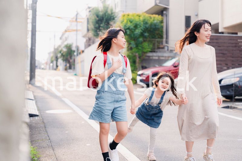 お母さんと手を繋いで学校に行く2人の女の子