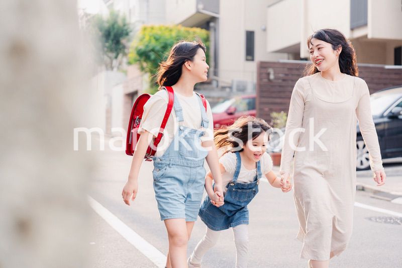 お母さんと手を繋いで学校に行く2人の女の子
