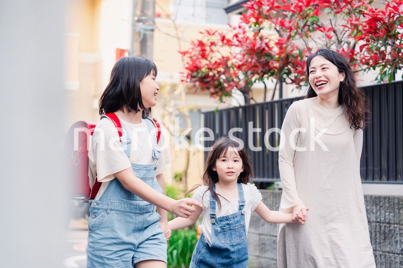 お母さんと手を繋いで学校に行く2人の女の子