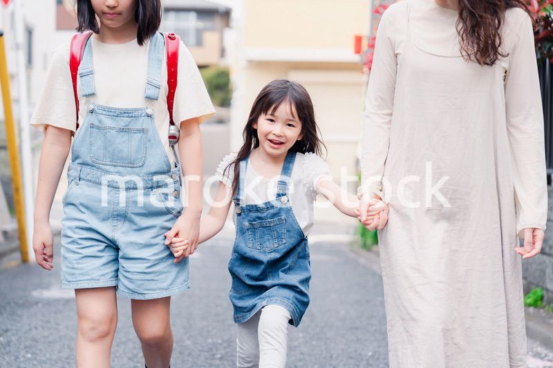 お母さんと手を繋いで学校に行く2人の女の子