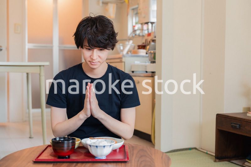 一人暮らしの下宿先でごはんを食べる若い男性