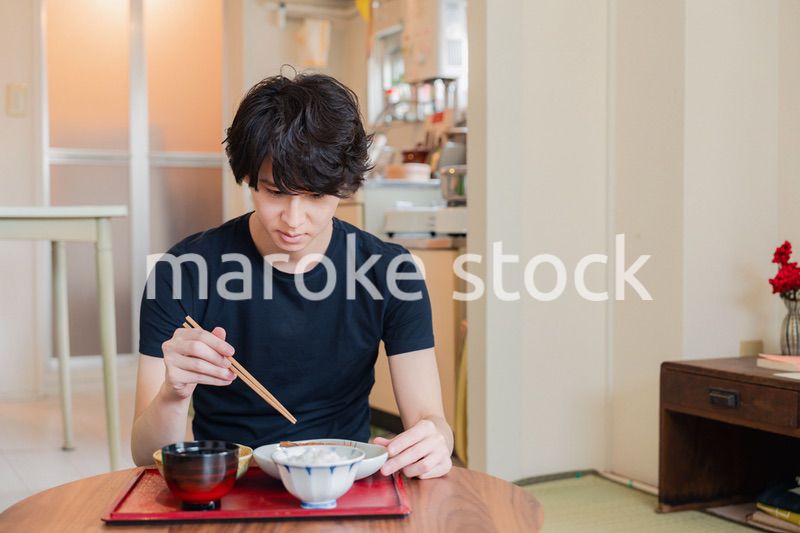 一人暮らしの下宿先でごはんを食べる若い男性