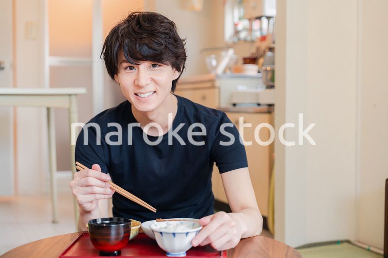 一人暮らしの下宿先でごはんを食べる若い男性