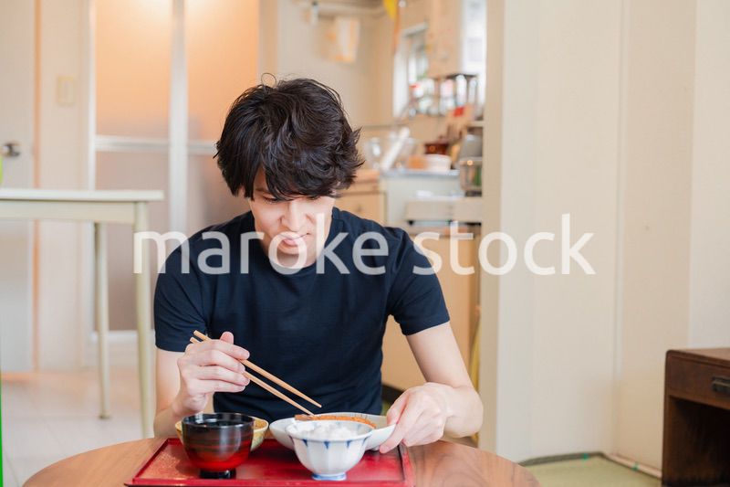 一人暮らしの下宿先でごはんを食べる若い男性