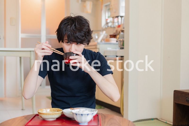 一人暮らしの下宿先でごはんを食べる若い男性