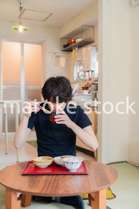一人暮らしの下宿先でごはんを食べる若い男性