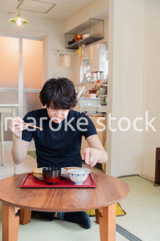 一人暮らしの下宿先でごはんを食べる若い男性
