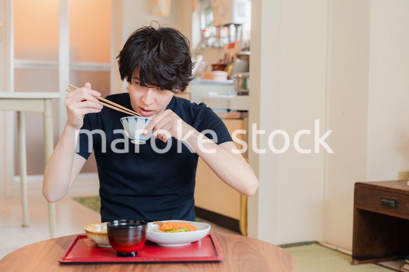 一人暮らしの下宿先でごはんを食べる若い男性