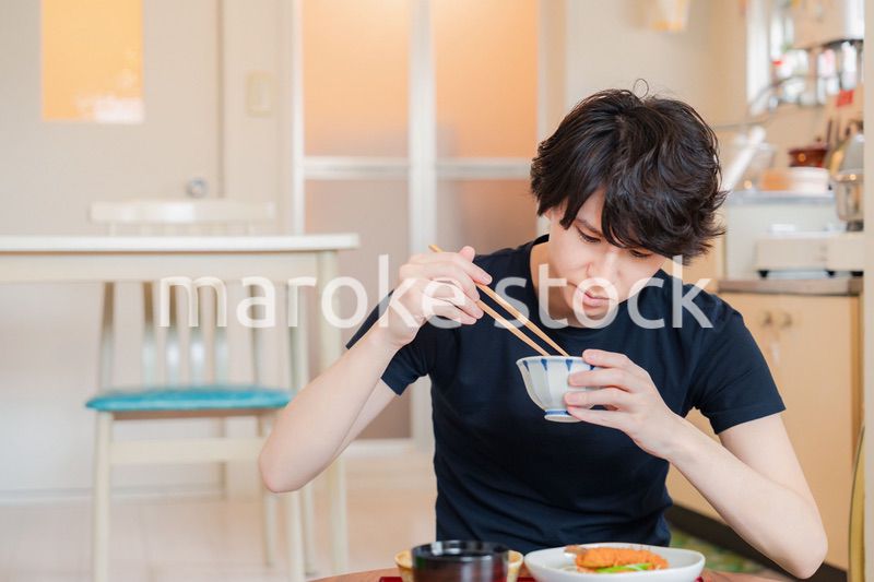 一人暮らしの下宿先でごはんを食べる若い男性