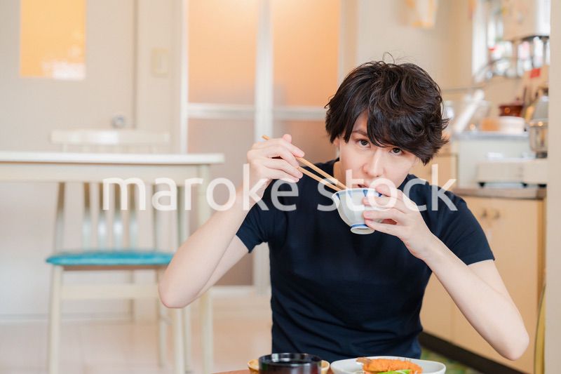 一人暮らしの下宿先でごはんを食べる若い男性