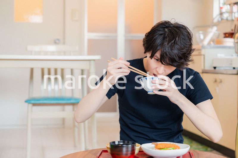 一人暮らしの下宿先でごはんを食べる若い男性