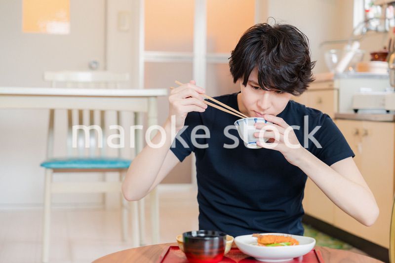 一人暮らしの下宿先でごはんを食べる若い男性