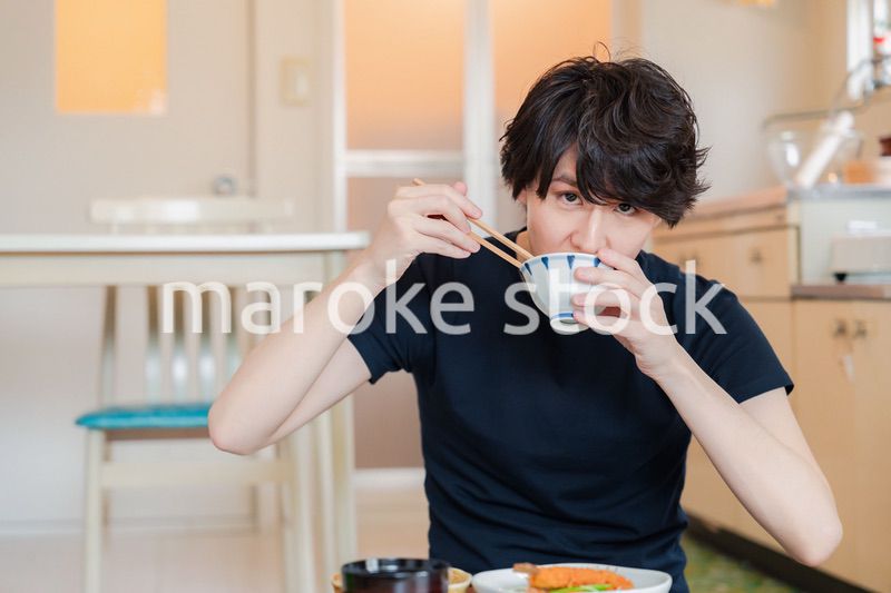 一人暮らしの下宿先でごはんを食べる若い男性