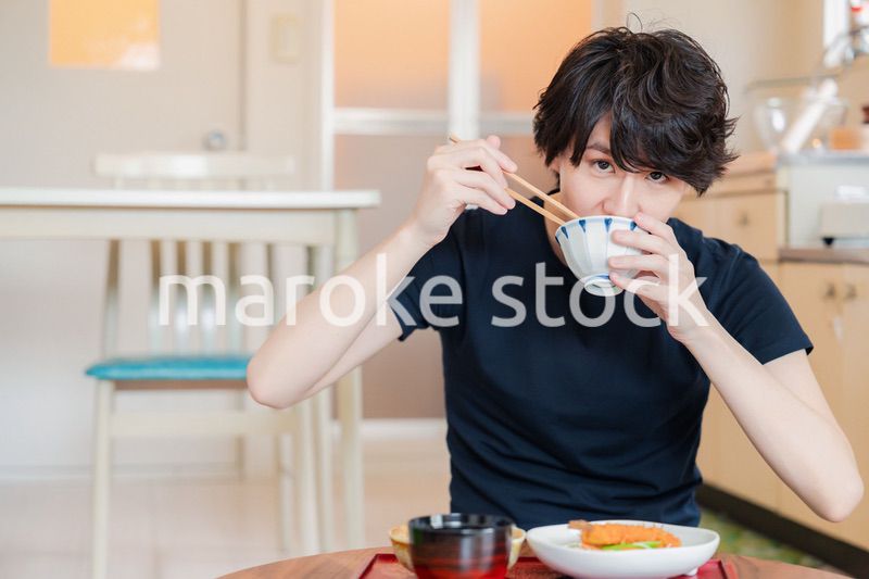 一人暮らしの下宿先でごはんを食べる若い男性