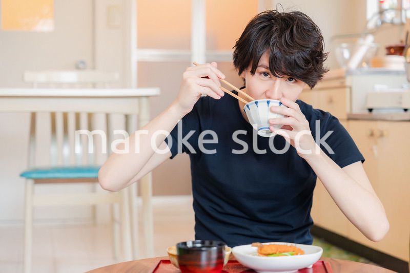 一人暮らしの下宿先でごはんを食べる若い男性