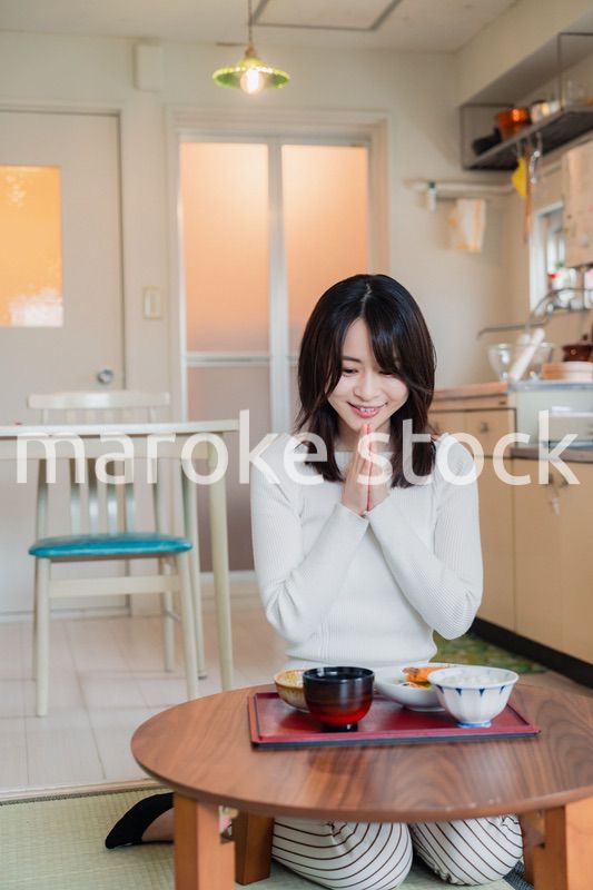質素な家でごはんを食べる一人暮らしの女性