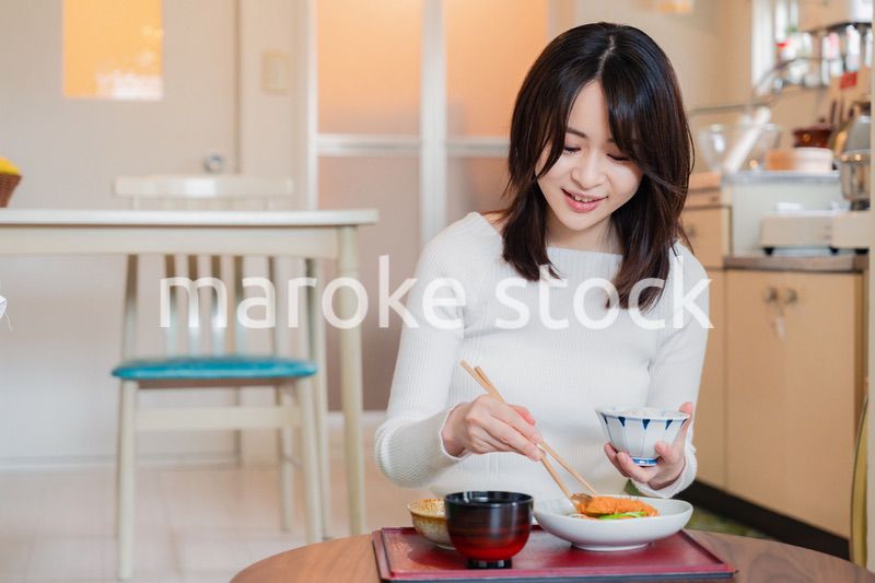 質素な家でごはんを食べる一人暮らしの女性