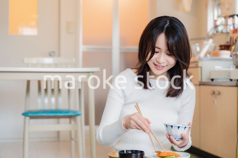 質素な家でごはんを食べる一人暮らしの女性