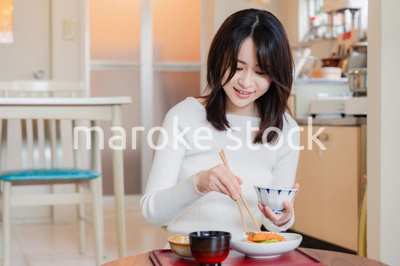 質素な家でごはんを食べる一人暮らしの女性