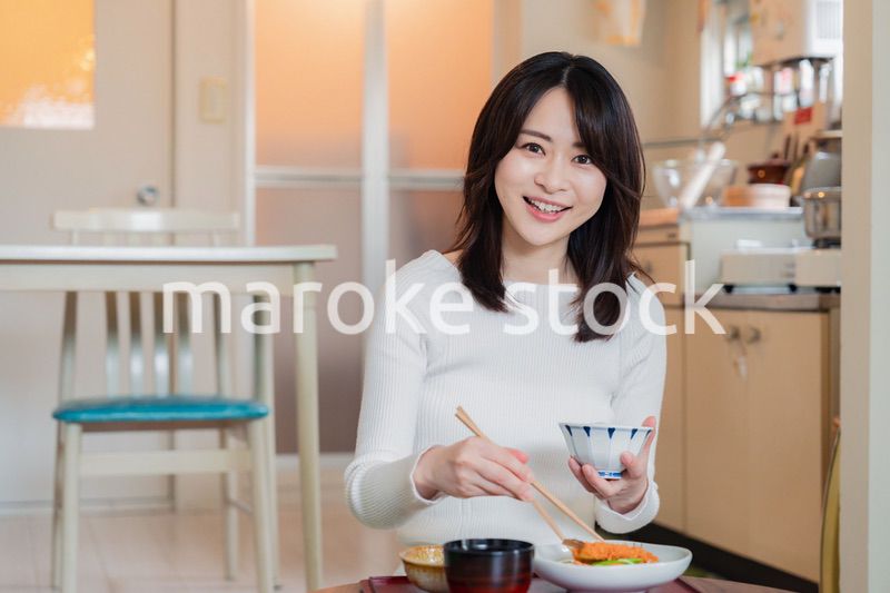 質素な家でごはんを食べる一人暮らしの女性