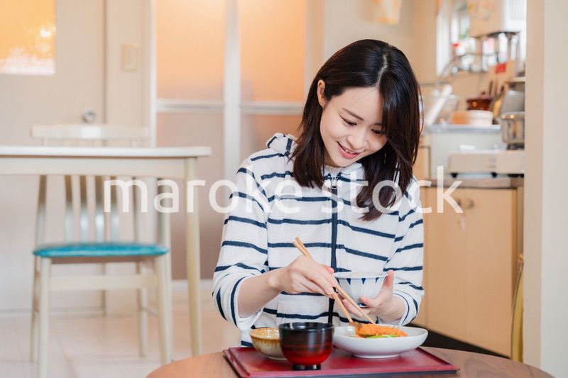 質素な家でごはんを食べる一人暮らしの女性