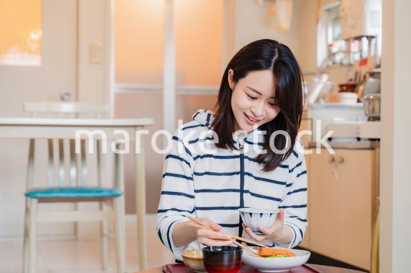 質素な家でごはんを食べる一人暮らしの女性