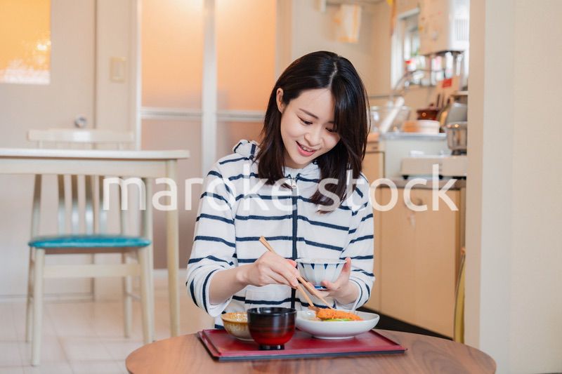 質素な家でごはんを食べる一人暮らしの女性