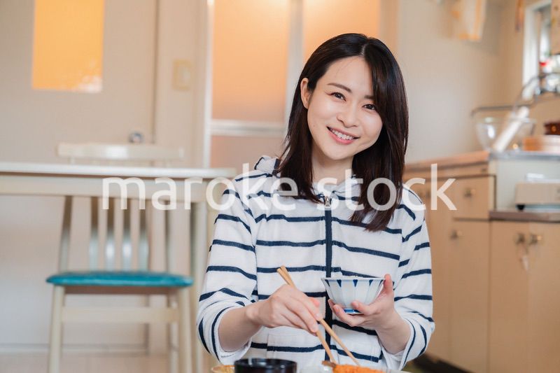 質素な家でごはんを食べる一人暮らしの女性