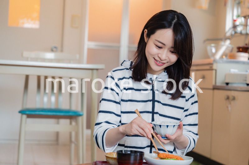 質素な家でごはんを食べる一人暮らしの女性