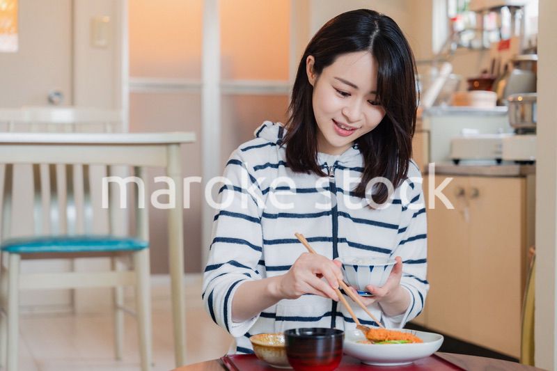 質素な家でごはんを食べる一人暮らしの女性