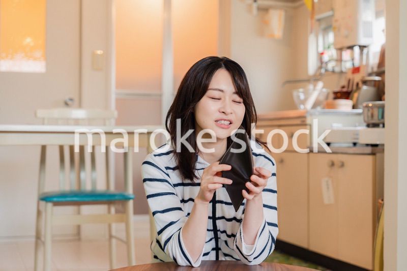財布の中を確認して落ち込む若い女性