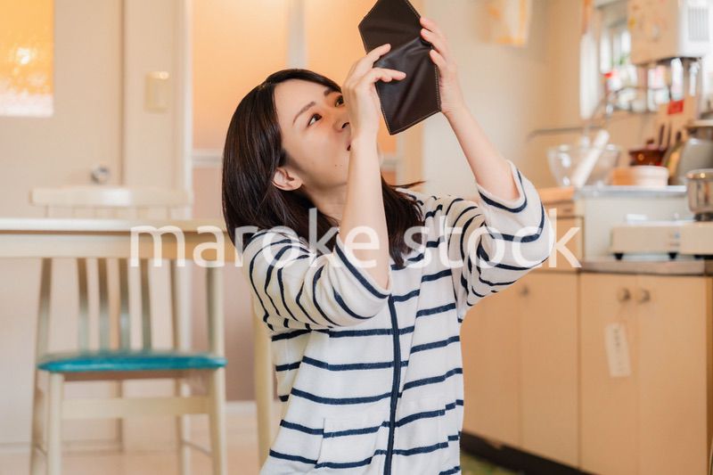 財布の中を確認して落ち込む若い女性