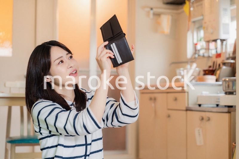 財布の中を確認して落ち込む若い女性