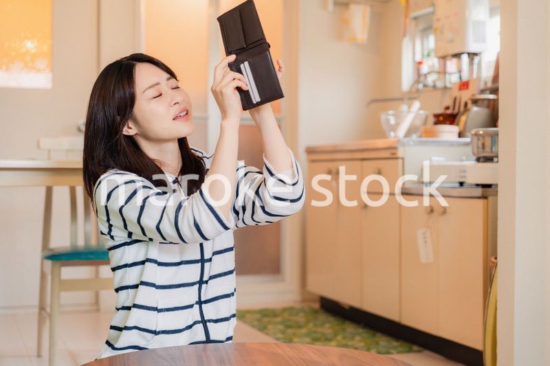 財布の中を確認して落ち込む若い女性
