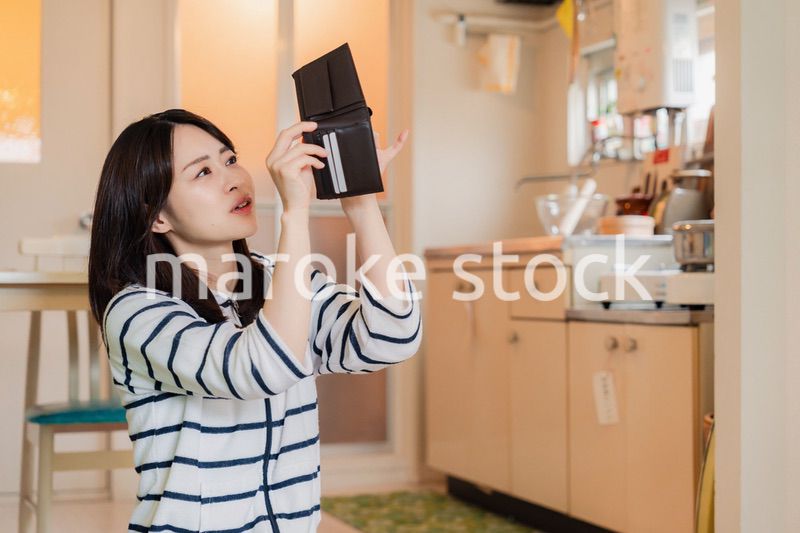 財布の中を確認して落ち込む若い女性